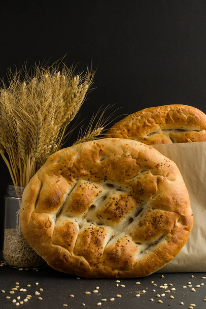 Traditional Turkish,Fresh,Circular Ramadan Bread in craft paper bag on black background with natural wheat ears.Conceptual image of Ramadan. - Foto, immagini