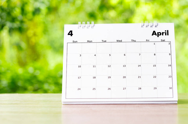 Календарь на апрель 2022 года для организатора планировать и напоминать на деревянном столе на природе. - Фото, изображение