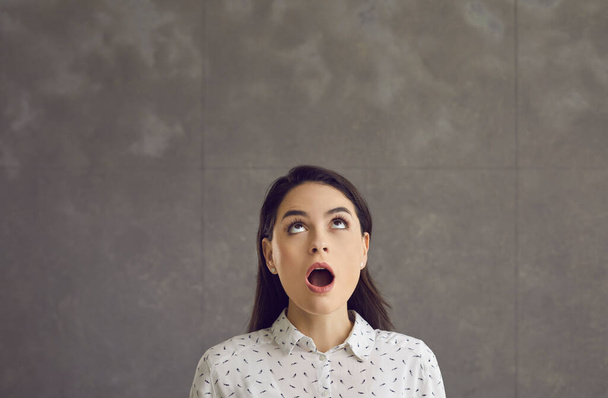 Young caucasian woman with opened mouth looking up feeling shock emotion - Фото, изображение