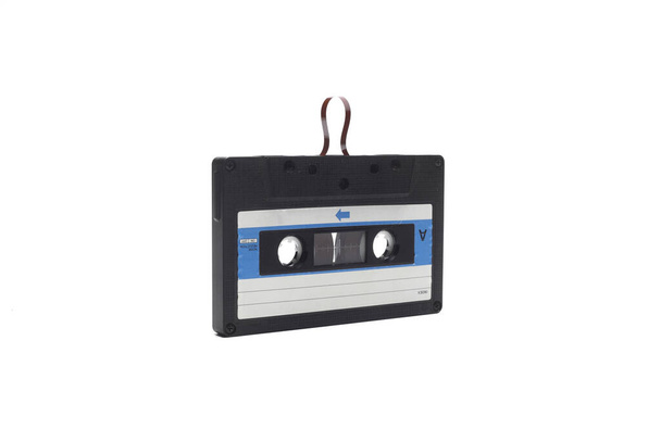 This shows a well known problem with the old fashioned compact cassettes: the tape used to come out, making the cassette useless. Vintage compact cassette tape on white background. - Photo, Image