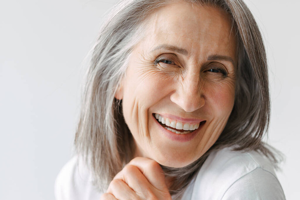 Grey senior woman in t-shirt laughing and looking at camera isolated over white background - Φωτογραφία, εικόνα