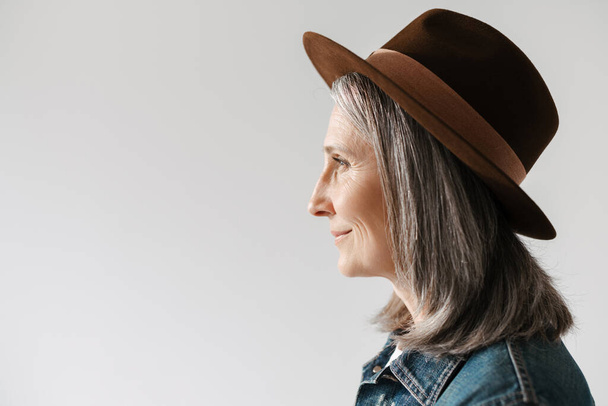 Grey senior woman in hat smiling and looking aside isolated over white background - Foto, Imagem