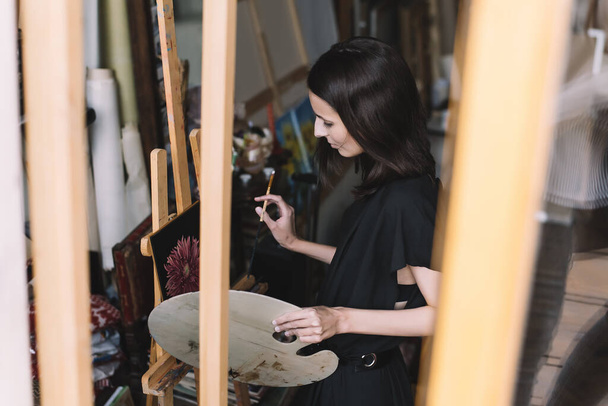 Modern art. Inspiration and creativity. Female painter at workshop studio. Pensive young lady working on her artwork. - Φωτογραφία, εικόνα