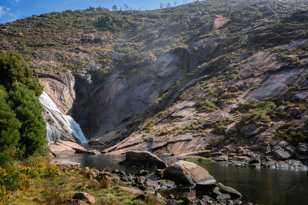 Ezaro waterfall water crashing on lake between rocks in Spain - Foto, afbeelding