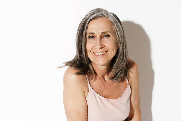 Mature grey woman smiling and looking at camera isolated over white wall - Photo, Image