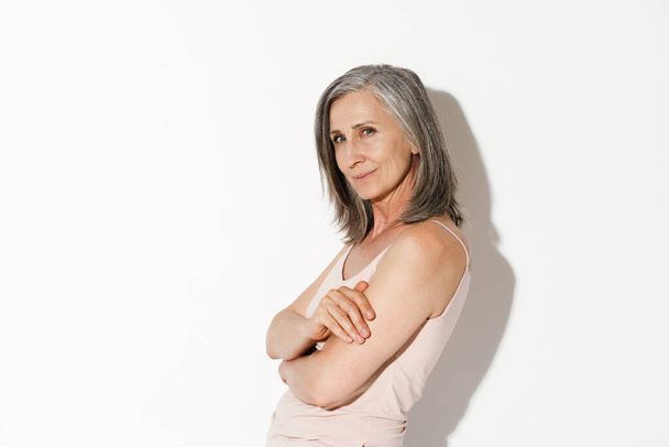Mature grey woman smiling and looking at camera isolated over white wall - Foto, immagini