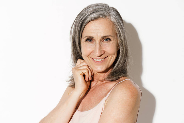 Mature grey woman smiling and looking at camera isolated over white wall - Foto, Bild
