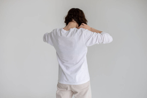 Rear view of a young woman with curly hair wearing a long sleeve t-shirt. Mock-up. - Foto, imagen