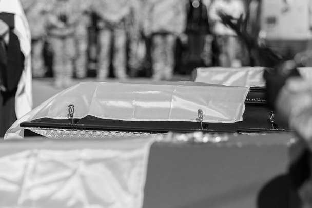POLTAVA, UCRANIA - 17 de marzo de 2022: ataúdes rojos de madera cubiertos con banderas ucranianas con víctimas del ataque ruso a Ucrania durante el funeral - Foto, imagen