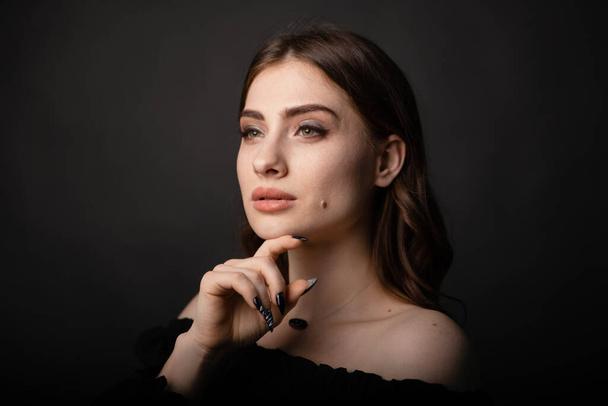 Portrait of a beautiful girl on a dark plain background. Stylish photo in the studio. - Photo, Image