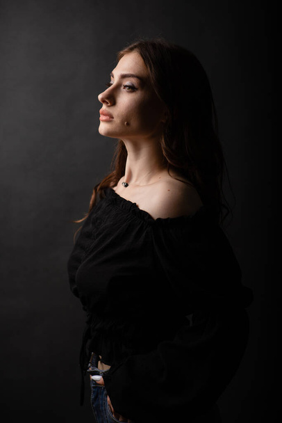 Porträt eines schönen Mädchens vor dunklem Hintergrund. Stilvolles Foto im Atelier. - Foto, Bild