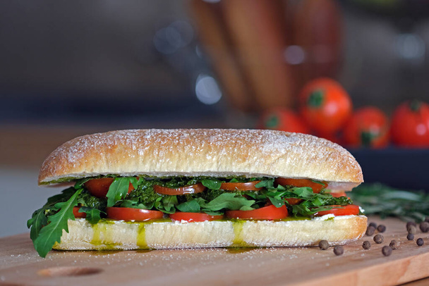 Heerlijke sandwich met ciabatta brood, tomaten, mozzarella, basilicum, kaas, pesto saus, verse arugula bladeren. Gezond eten. Italiaanse keuken. Vegetarisch kookconcept. Fastfood koken - Foto, afbeelding