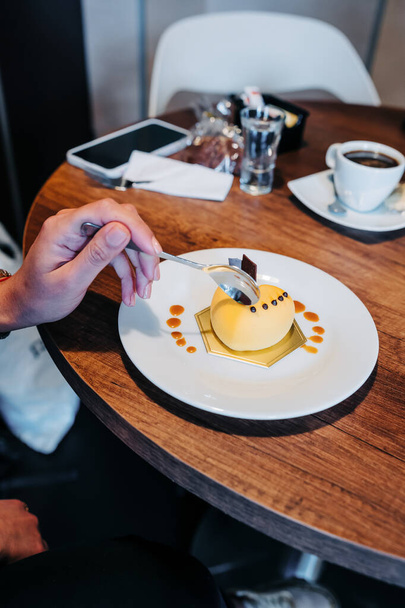 beautifully decorated delicious gourmet dessert, person's hand holding spoon and eating, elegant lifestyle, confectionery, texture details - Fotó, kép