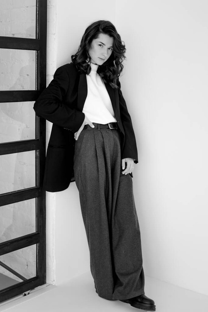 black and white portrait of young stylish woman wearing wide pants and jacket - Фото, изображение