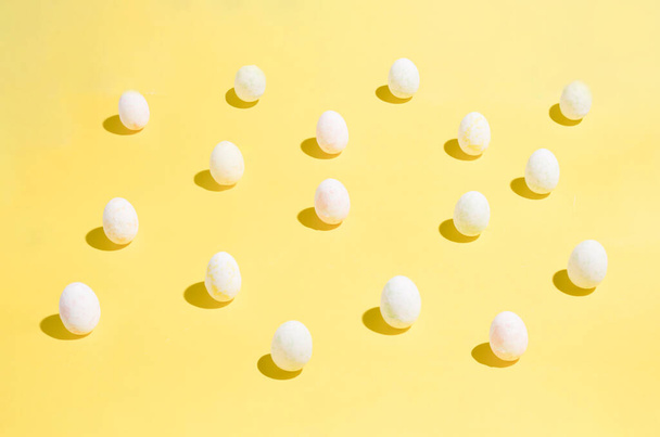 Huevos de Pascua patrón caótico sobre fondo de color amarillo. Feliz concepto de Pascua. Un plano minimalista simple acostado vista superior. - Foto, Imagen