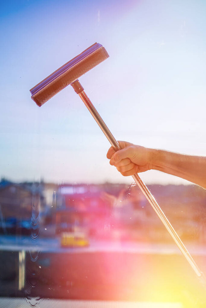 Window cleaning in high-rise buildings, houses with a brush. Window cleaning brush. Large window in a multi-storey building, cleaning service. Dust removal and glass washing. - Photo, image