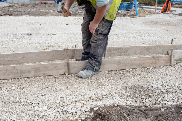 Затвор для бетона, чтобы сформировать основу для бордюра с использованием каркасов и штифтов стальных дорог во время нового строительства дороги - Фото, изображение