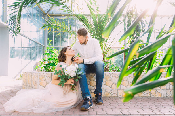 romantic couple looks at each other in a botanical garden near greenery - Photo, Image
