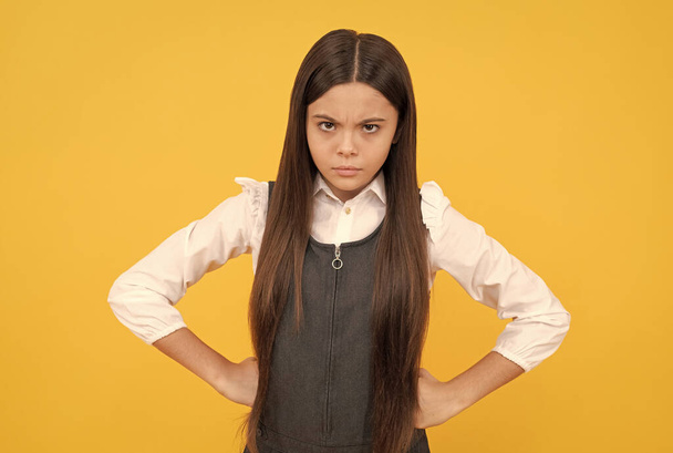 Becoming disobedient. Disobedient child yellow background. Frown girl stand with arms akimbo - Photo, Image