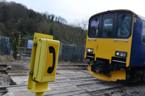 Oblique kąt widzenia ogólny telefon alarmowy przez przejazd kolejowy jak pociąg zbliża - Zdjęcie, obraz