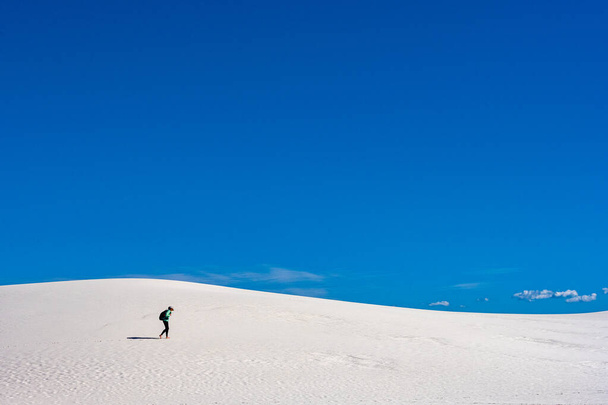 Ένας πεζοπόρος διασχίζει λευκό αμμόλοφο κάτω από μπλε ουρανό στο πάρκο του Νέου Μεξικού - Φωτογραφία, εικόνα
