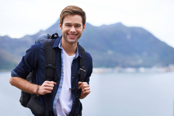 Best hiking destination. Portrait of a handsome young man standing with a backpack in the outdoors. - Fotó, kép