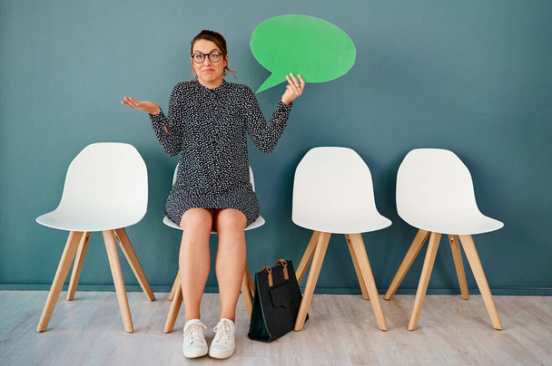 What more can I say. Studio portrait of an attractive young businesswoman holding up a speech bubble while sitting in line against a grey background. - Photo, Image