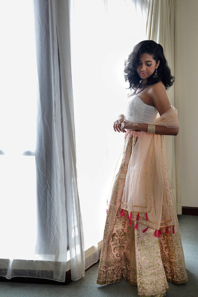 美しい若い女性を身に着けているインドスタイルのロイヤルティドレスジュエリーライトメイクレトロヴィンテージファッション窓の光の横に - 写真・画像