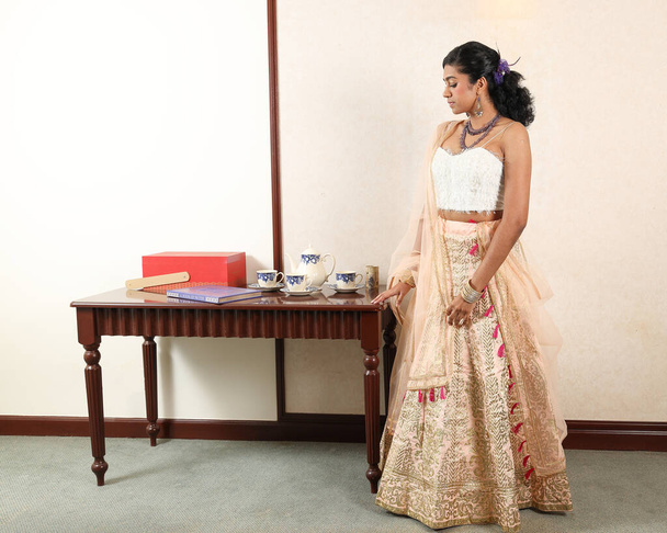 Hermosa mujer joven que usa moderno indio lehenga hgagra tobillo longitud falda vestido posando casa retro vintage - Foto, Imagen