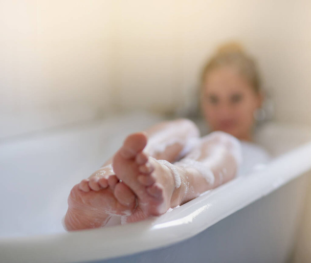 Let all your worries just drift away. Shot of a beautiful young woman relaxing in the bathtub. - 写真・画像