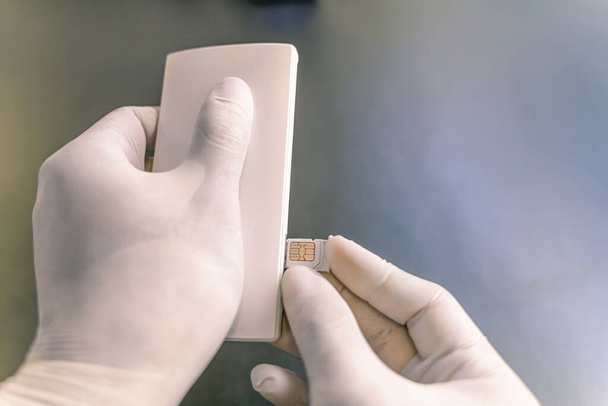 Ręka człowieka w gumowej ochronnej, personel zmienić kartę SIM, sprzedaży symulator podróży w sklepie dla klientów do zakupu, środki 4K, aby zapobiec infekcji od koronawirusa - 19. - Zdjęcie, obraz