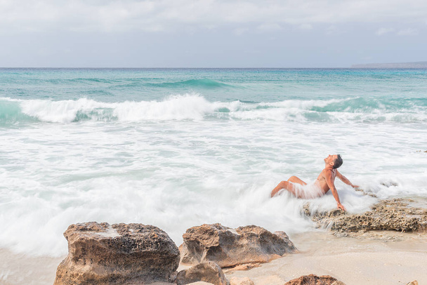 Male naturist sitting in waving sea. Formentera Island. - Foto, afbeelding