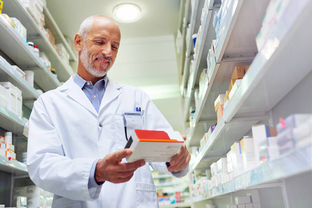 Hes meticulous when it comes to medicinal management. Shot of a mature pharmacist doing inventory in a pharmacy. - Photo, Image