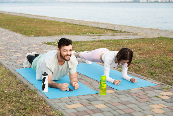 Sporty young couple doing plank near river - Fotografie, Obrázek