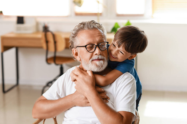 Kleiner Junge umarmt seinen Großvater zu Hause - Foto, Bild