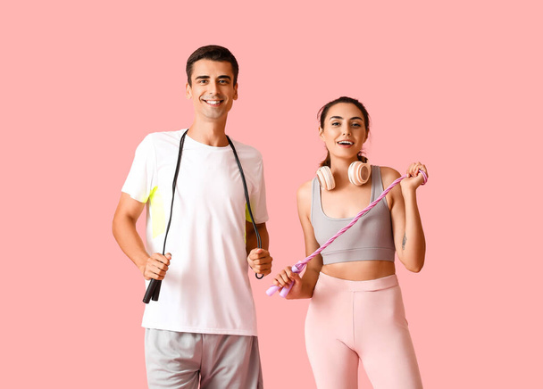 Sporty young couple with skipping ropes on color background - Valokuva, kuva