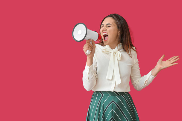 Angry young woman with megaphone  on color background - Photo, Image