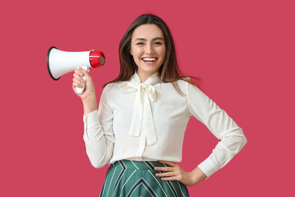 Счастливая молодая женщина с мегафоном на цветном фоне - Фото, изображение