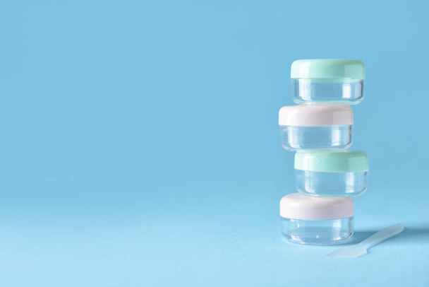 Set of empty travel cosmetic jars on blue background - Фото, зображення
