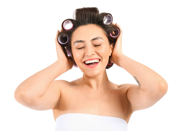 Happy young woman in hair curlers on white background - Photo, Image