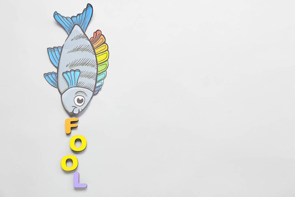 Samenstelling met papieren vis en woord FOOL op lichte ondergrond. April Fools Day viering - Foto, afbeelding