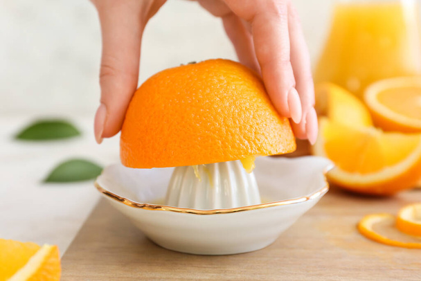 Woman squeezing fresh orange on light background - Photo, Image