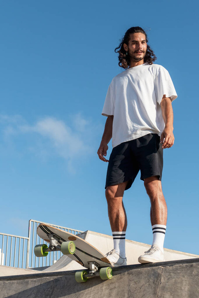 Junger kaukasischer Skater steht am Rand der Skaterrampe - Foto, Bild