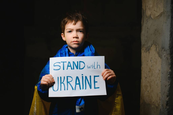 Russia's war against Ukraine in 2022. A sad boy is hiding in a bomb shelter from Russian missiles. Stop the war. - Zdjęcie, obraz