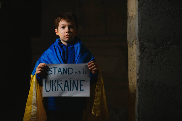 Russia's war against Ukraine in 2022. A sad boy is hiding in a bomb shelter from Russian missiles. Stop the war. - Photo, Image