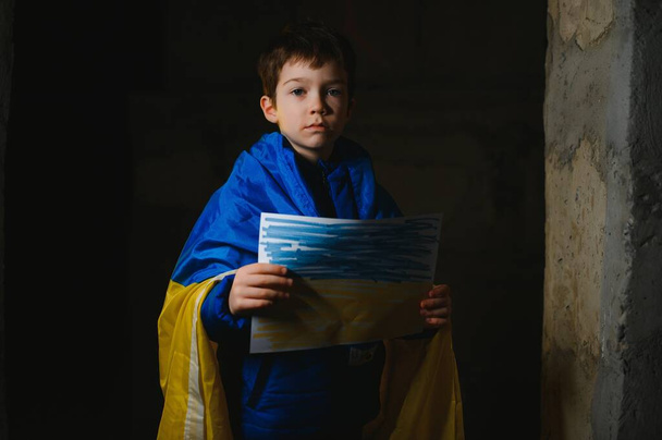 Ukrainian Crying boy holds a painted flag of Ukraine. War of Russia against Ukraine. Ukrainian Crying boy asks to stop the war in Ukraine. Child with message Stop War. - Foto, Imagen