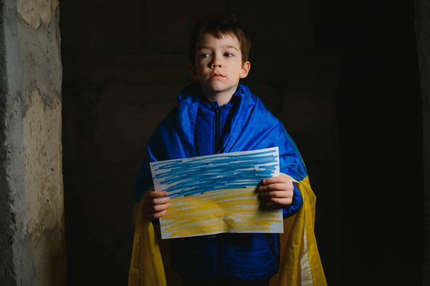 Ukrainan itkevä poika omistaa maalattu lippu Ukrainan. Venäjän sota Ukrainaa vastaan. Ukrainan itkupoika pyytää lopettamaan sodan Ukrainassa. Lapsi viestin kanssa Stop War. - Valokuva, kuva