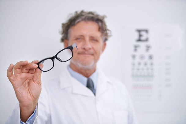 Mantén tus ojos en las últimas tendencias en gafas. Retrato de un optometrista maduro sosteniendo un par de gafas. - Foto, Imagen