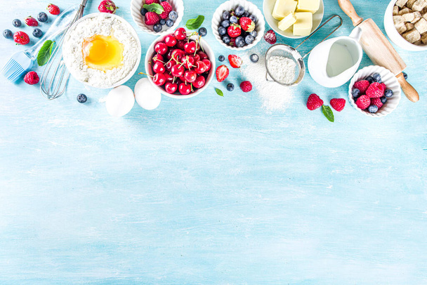 Рецепт випічки ягідного торта. Літній кулінарний фон для випічки з певними ягодами, інгредієнтами для випічки, інструментами та посудом, світло-блакитним сонцем, освітленим дерев'яним фоном, плоский простір для копіювання зверху
 - Фото, зображення