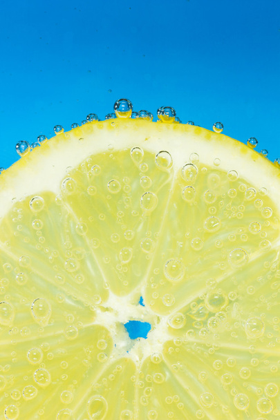 Nice fresh lemon covered with bubbles in soda. - Photo, Image